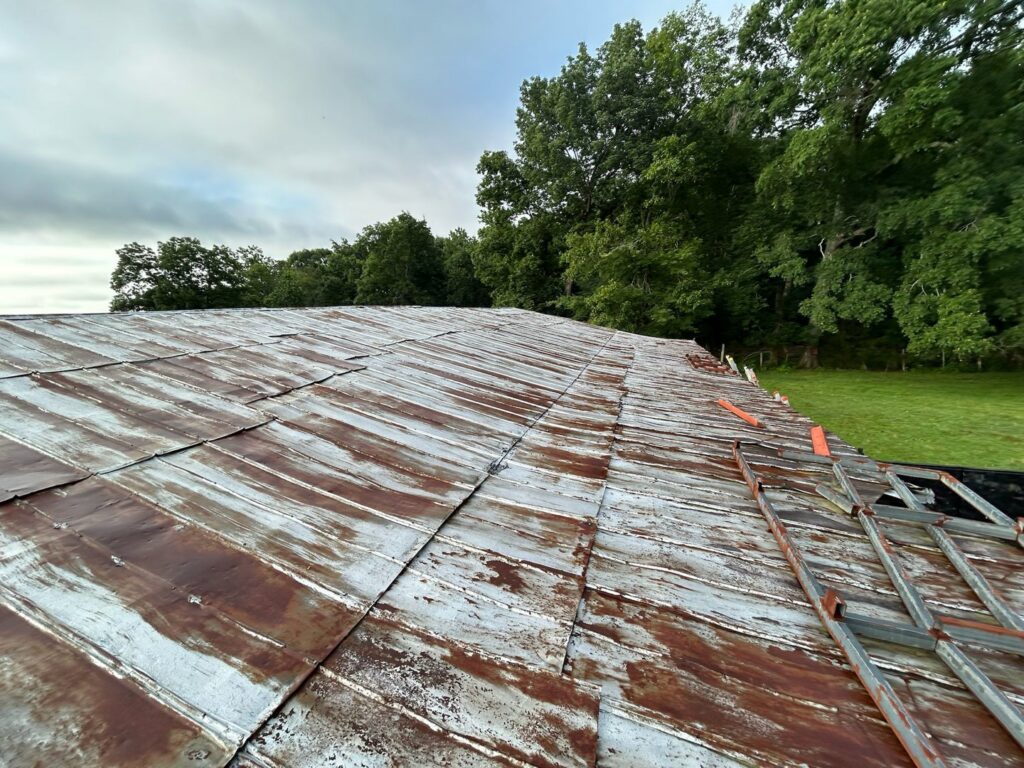 An old, rusty metal roof showing signs of wear, indicating a need for repair or replacement by Roofing Experts Care in Charlotte, NC.