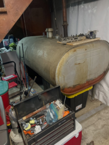 An old, rusty oil tank located in a basement, awaiting removal by DLS Junk Removal in Waterbury, CT.