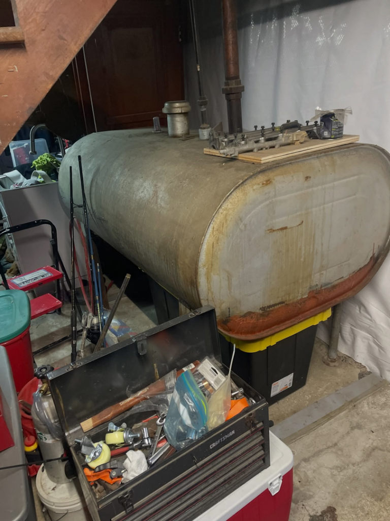 An old, rusty oil tank located in a basement, awaiting removal by DLS Junk Removal in Waterbury, CT.