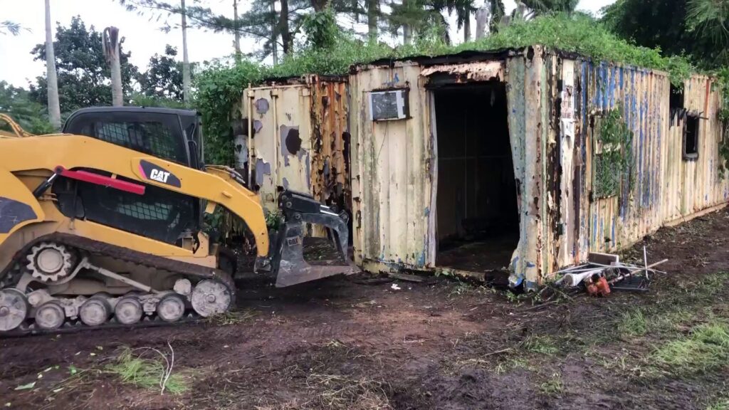 Gator Junk Removal using a skid steer to remove a dilapidated shipping container from a property in Miami, FL.
