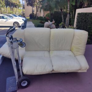 An old sofa placed on a dolly for furniture removal by Wilsa Junk Removal in Fort Lauderdale, FL.