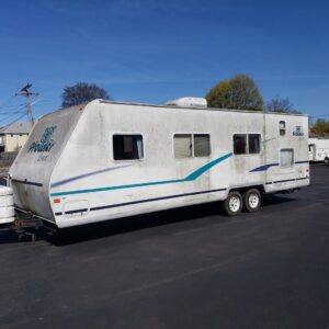 An old, dirty travel trailer in a parking lot, ready for removal by Green Clover in Quincy, MA.