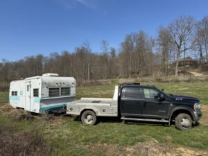 A truck from TRS Roll-Offs LLC towing an old travel trailer for removal, demonstrating junk removal services in Canton, OH.