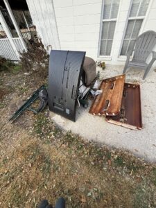 A pile of old TV, wooden panels, and other debris outside a house, ready for junk removal by Lightning Bay Junk Removal in Tampa, FL.