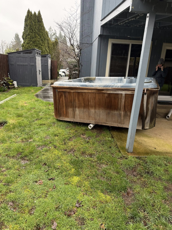 An old, weathered hot tub sitting on a patio, awaiting removal by AllStarr Solutions Hauling and Junk Removal in Newberg, OR.