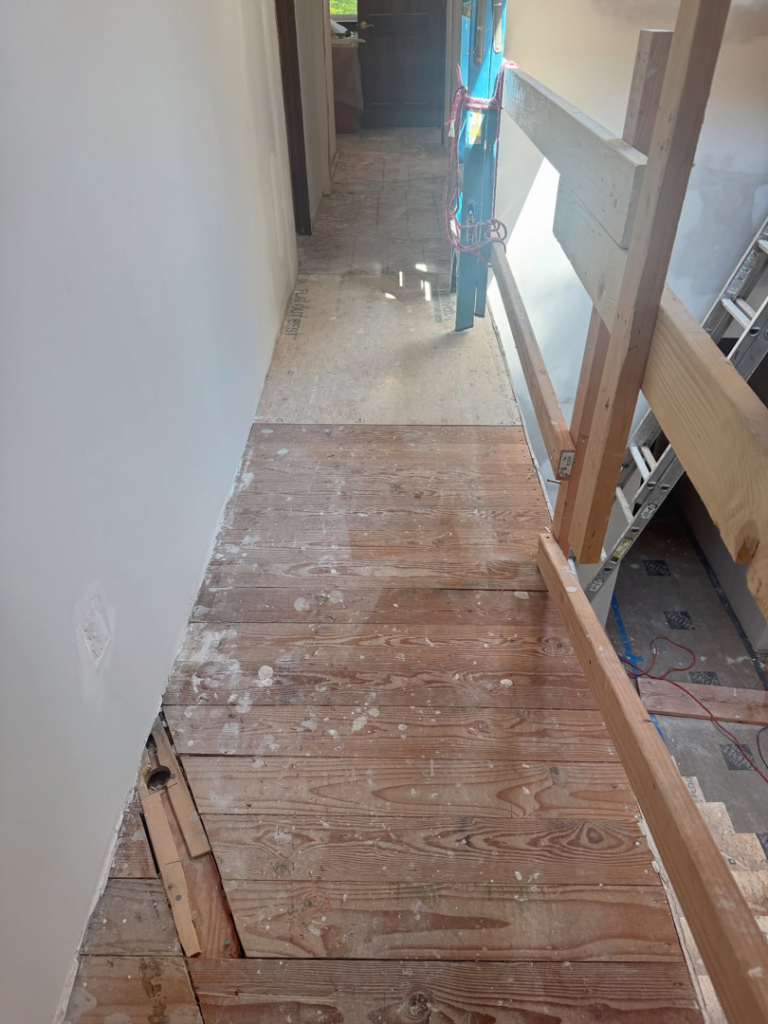 Old wooden floor undergoing renovation with a temporary railing by International Wood Floors in Gaithersburg, MD