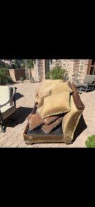 An old, worn-out couch with decorative pillows placed on a patio, ready for removal by The Junkporter Junk Removal in Las Vegas, NV.