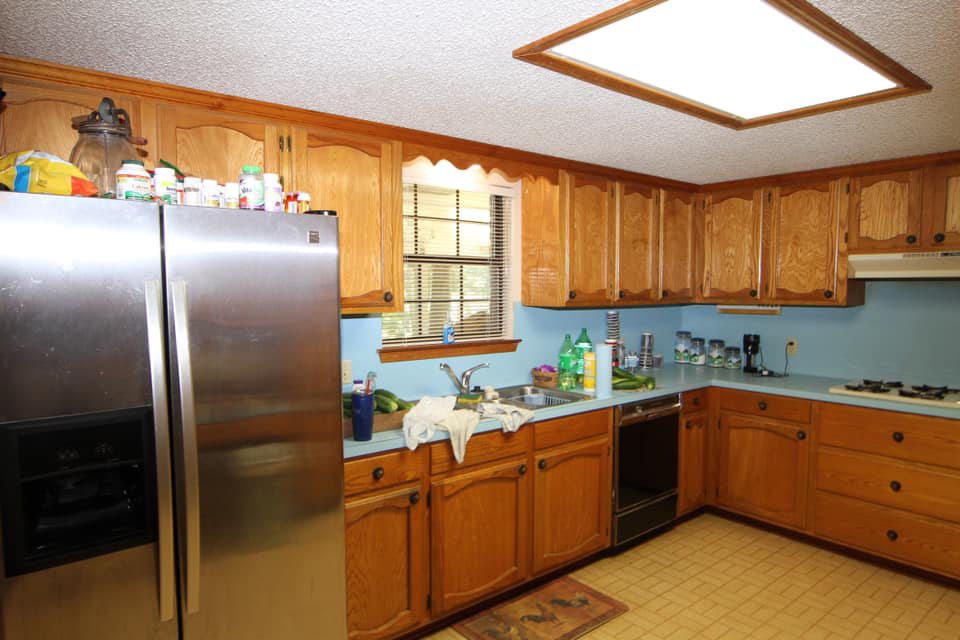 An older kitchen with wooden cabinets and blue countertops, shown before a remodel by Regal Remodelers in Baton Rouge, LA.