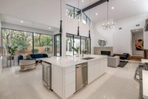 An open-concept home interior with a modern kitchen and living area by Stone Age Granite of Austin, TX.