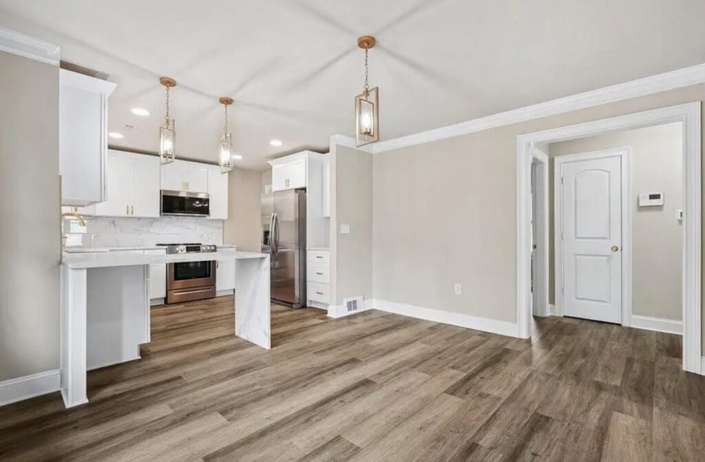 A bright, open-concept kitchen and dining area with new flooring and white cabinets by Ruach Home Services in Laurel, MD.