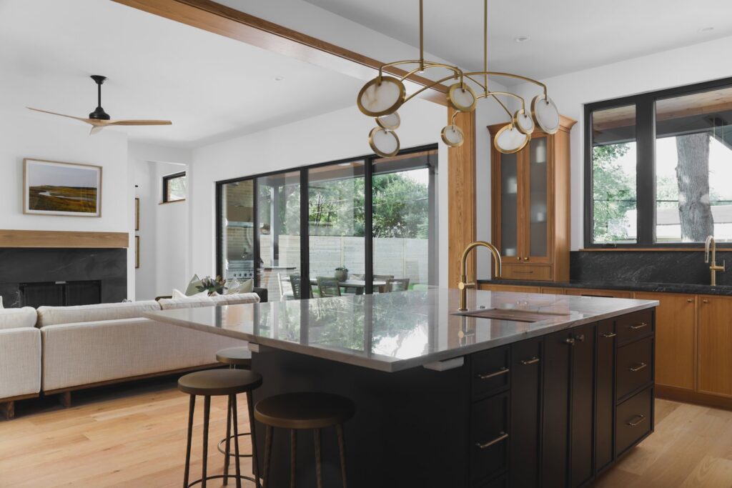 An open concept kitchen and living area featuring a large island and modern design elements by Stone Acorn Builders in Bellaire, TX.