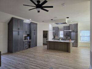 A spacious open-concept kitchen and living area with modern grey cabinets and a large island, part of a whole house remodel by Whole House Remodel & Design North Dallas Tx in Frisco, TX.