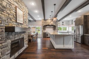 An open-concept kitchen and living area remodel with a stone fireplace and wood beams by All Star Construction, Inc. in Houston, TX.
