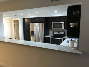 An open-concept kitchen remodel with dark cabinets and a breakfast bar by BRM Construction in Miami, FL.
