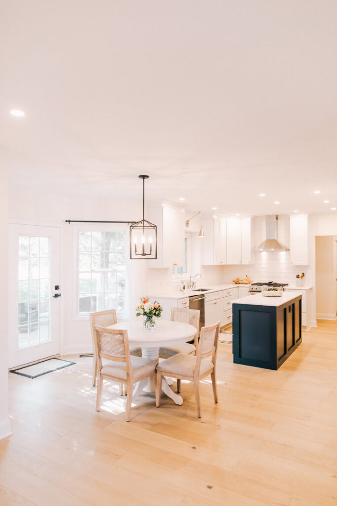 A stunning open-concept kitchen remodel with white cabinets, a dark island, and hardwood floors by Knaub Home Solutions in Rochester, NY.