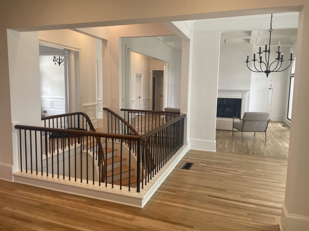 An open concept living area with newly installed light hardwood floors and stairs by Glenni Floors LLC in Roswell, GA.