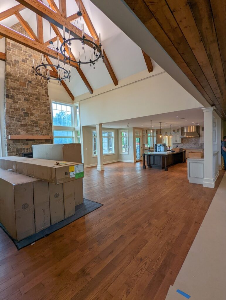 Open concept living area renovation with exposed beams and stone fireplace by Roche Painting in Allentown, PA.