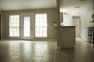 An open-concept living area and kitchen featuring new tiled floors, large windows, and white kitchen cabinets, remodeled by Custer Remodeling in Plano, TX.