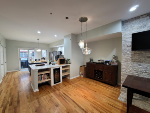 An open-concept living and kitchen area with new hardwood floors and a stone feature wall by FAV Remodeling Services LLC in Gurnee, IL.