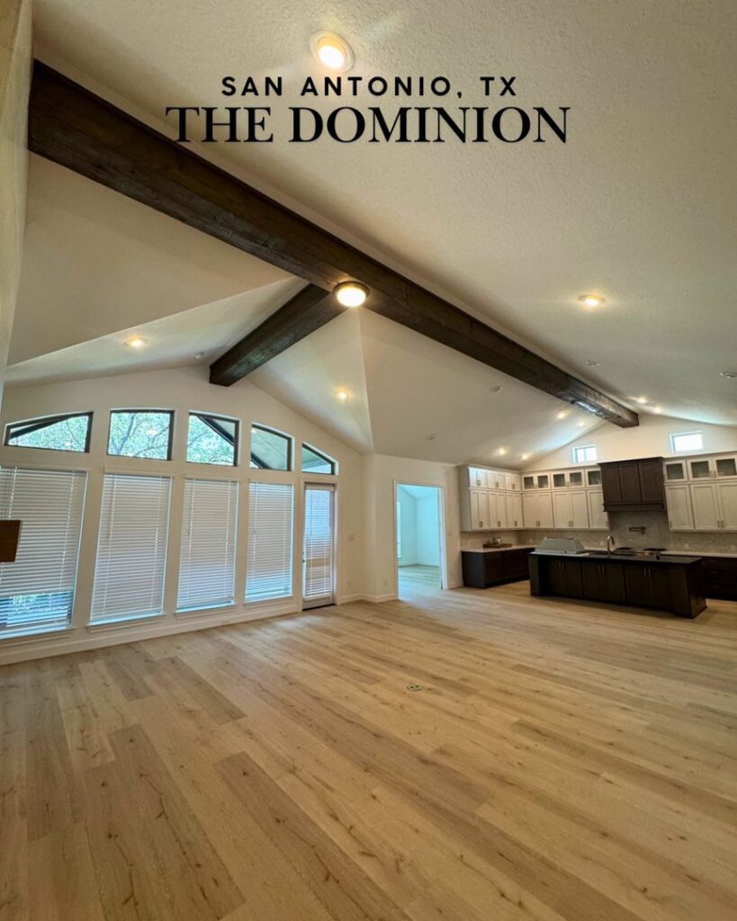 An open-concept living and kitchen area with exposed beams and wood flooring, showcasing a renovation by Roaring Lion Renovations, LLC in Houston, TX.