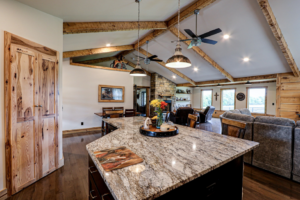 An open-concept living room and kitchen area with exposed wooden beams and ceiling fans by GCU Custom Builders in Louisville, KY.