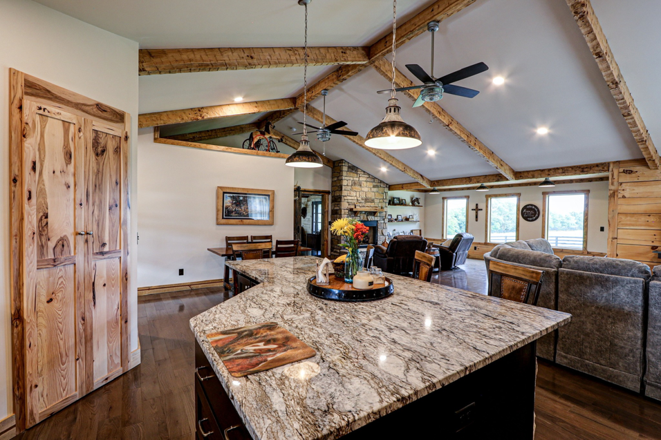 An open-concept living room and kitchen area with exposed wooden beams and ceiling fans by GCU Custom Builders in Louisville, KY.