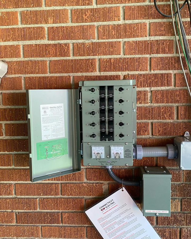 An open electrical transfer switch or subpanel installed on a brick wall by Gingy's Electrical Services, LLC in Memphis, TN.