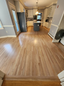 An open-plan kitchen and dining area with continuous light hardwood flooring installed by floorzone.inc in Los Angeles, CA.