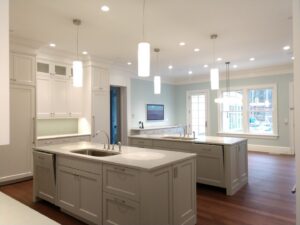 A large, open-plan kitchen with two islands, white cabinets, and pendant lighting by Santoro Home Improvements in Wallingford, CT.