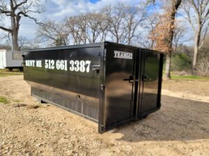 An open black roll-off dumpster from Team512 with 'RENT ME' signage, ready for waste disposal in Austin, TX