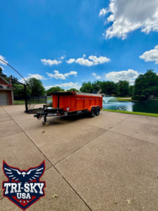 An orange dump trailer used for junk removal services by Tri-Sky USA in Evansville, IN.