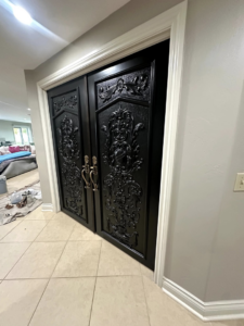 Newly installed or painted ornate black double doors with fresh white trim, showcasing a home improvement project by Joe's Home Services in Manchester, NH.