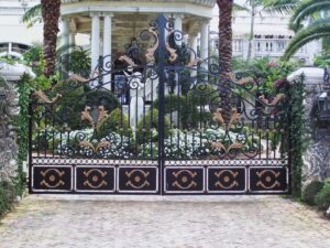 Ornate black and gold wrought iron driveway gate installed by Xclusive Fence And Rails Inc. in Miami, FL.