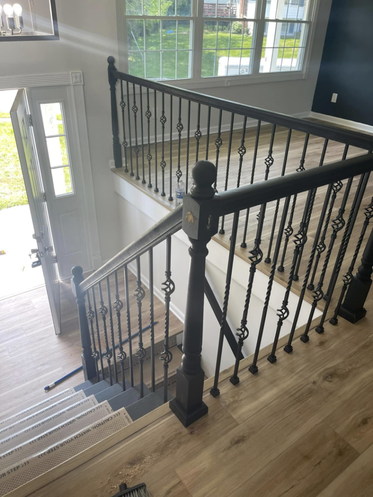 An interior staircase featuring ornate black iron railings and newel posts by AC Fence and Ironworks in Philadelphia, PA.