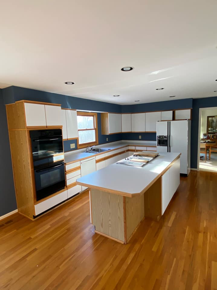 An outdated kitchen with wood-paneled cabinets and built-in ovens, ready for a remodel by KLS Remodel in Cincinnati, OH.