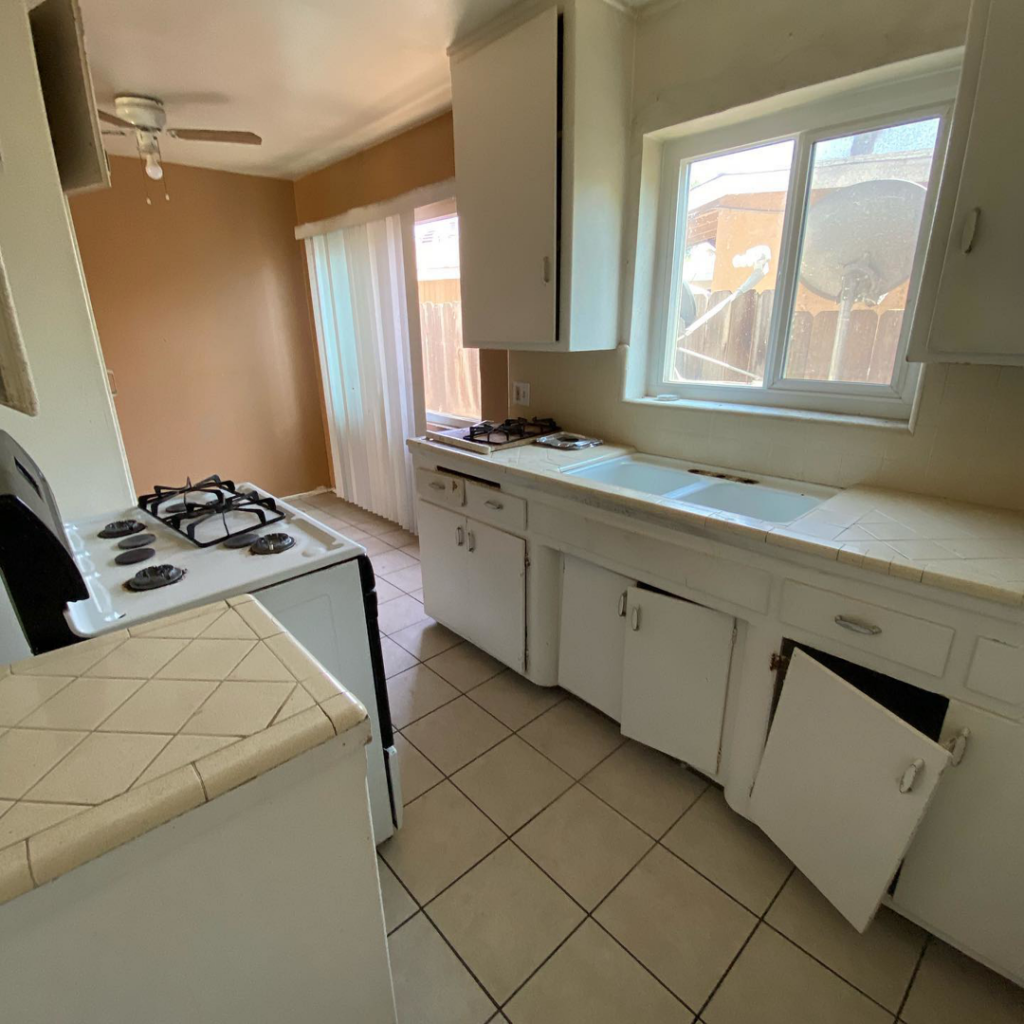 An outdated kitchen with old cabinets and tile countertops, ready for renovation by Premier Home Services in Fullerton, CA