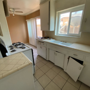 An outdated kitchen with old cabinets and tile countertops, ready for renovation by Premier Home Services in Fullerton, CA