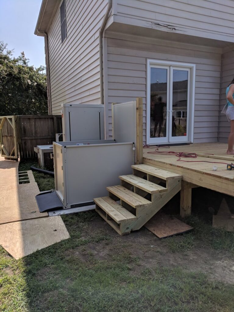 An outdoor accessibility lift and new wooden deck stairs installed by The Home Pros in Virginia Beach, VA