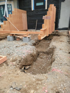 Outdoor construction site with wooden concrete forms and trenches by Smith Finishes LLC in Everett, WA.