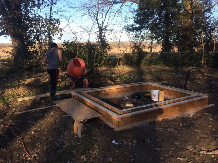 An outdoor construction project with a concrete mixer and a person working, handled by The Hot Handyman in Lawrence, KS.