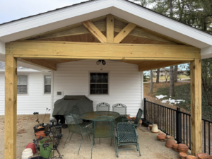 A newly constructed outdoor covered patio featuring a wooden gable roof and support beams by Rogers Remodeling in Bloomington, IN.