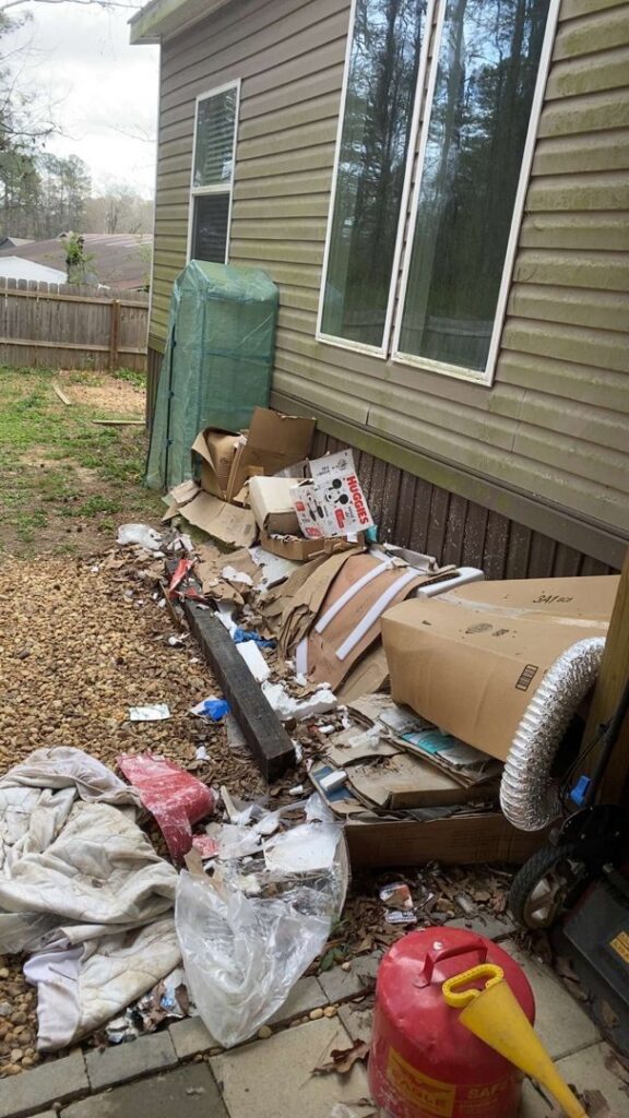 An outdoor pile of cardboard boxes and debris next to a house, ready for junk removal by Marc & Park Junk Removal, LLC in Birmingham, AL.
