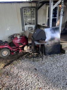 Outdoor debris including a riding lawnmower and grill awaiting removal by Haul It All Debris & Junk Removal in Henderson, NV
