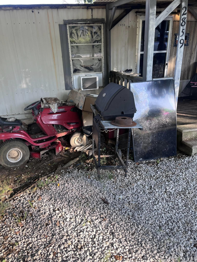 Outdoor debris including a riding lawnmower and grill awaiting removal by Haul It All Debris & Junk Removal in Henderson, NV