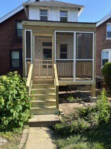 A newly built outdoor wooden deck with a staircase leading to a patio area, completed by McIntosh Construction in Des Peres, MO.