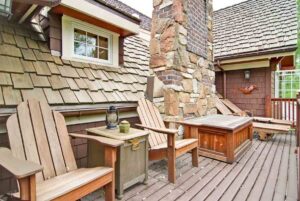 An outdoor deck with wooden chairs and a stone chimney, a project by Northrup Remodeling in Minneapolis, MN