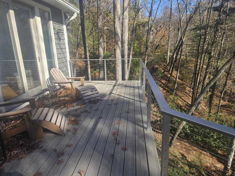 An outdoor deck with modern cable railing and wooden chairs by American Cable & Rigging in Mills River, NC.