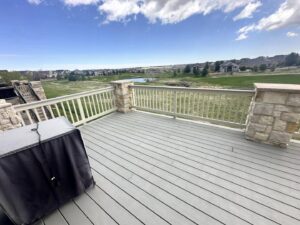 A spacious outdoor deck with stone and white railings built by Blue Collar Service Pros in Aurora, CO.
