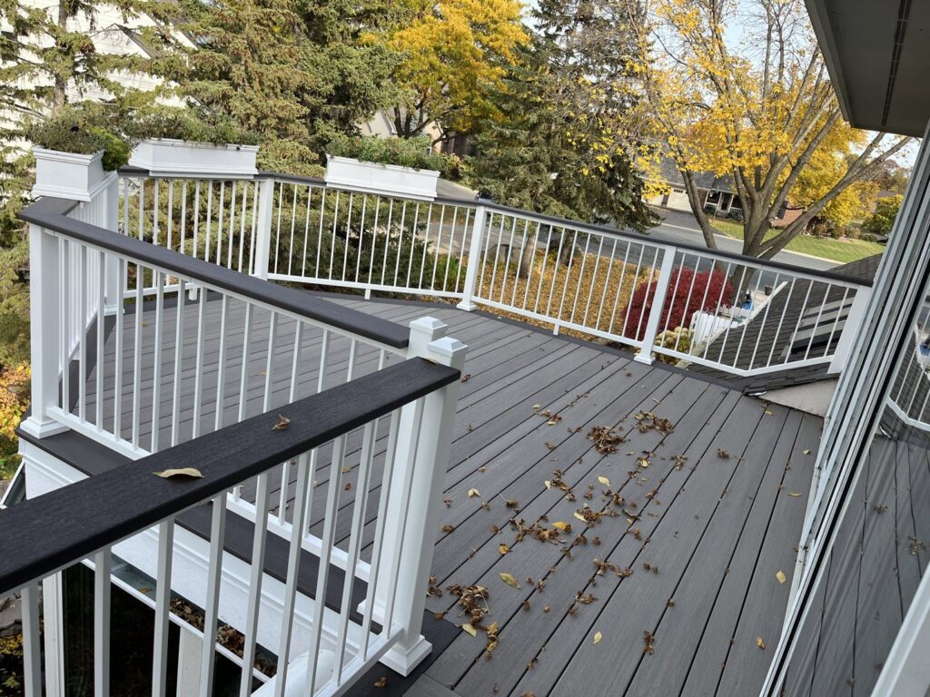 A newly constructed outdoor deck with white railings and dark composite decking, built by Inova Builds in Bloomington, MN.