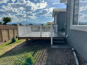 A newly constructed outdoor deck with white railings and composite decking by RK Pro Service Inc in Colorado Springs, CO.